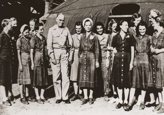 Vice Admiral Thomas C. Kinkaid, Commander, Seventh Fleet, poses with the liberated nurses on Leyte on 23 February 1945